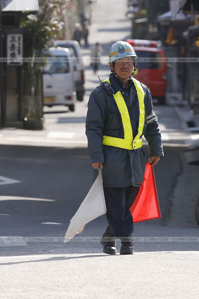 Person directing traffic with flags at roadworks