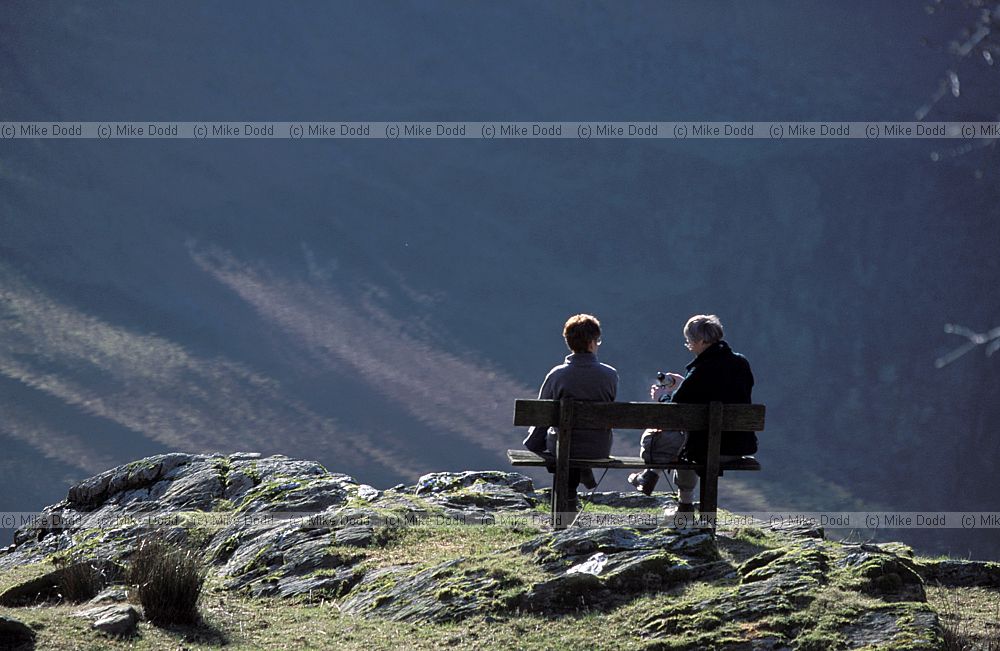 People sitting on seat having lunch overlooking Buttermere Lake district