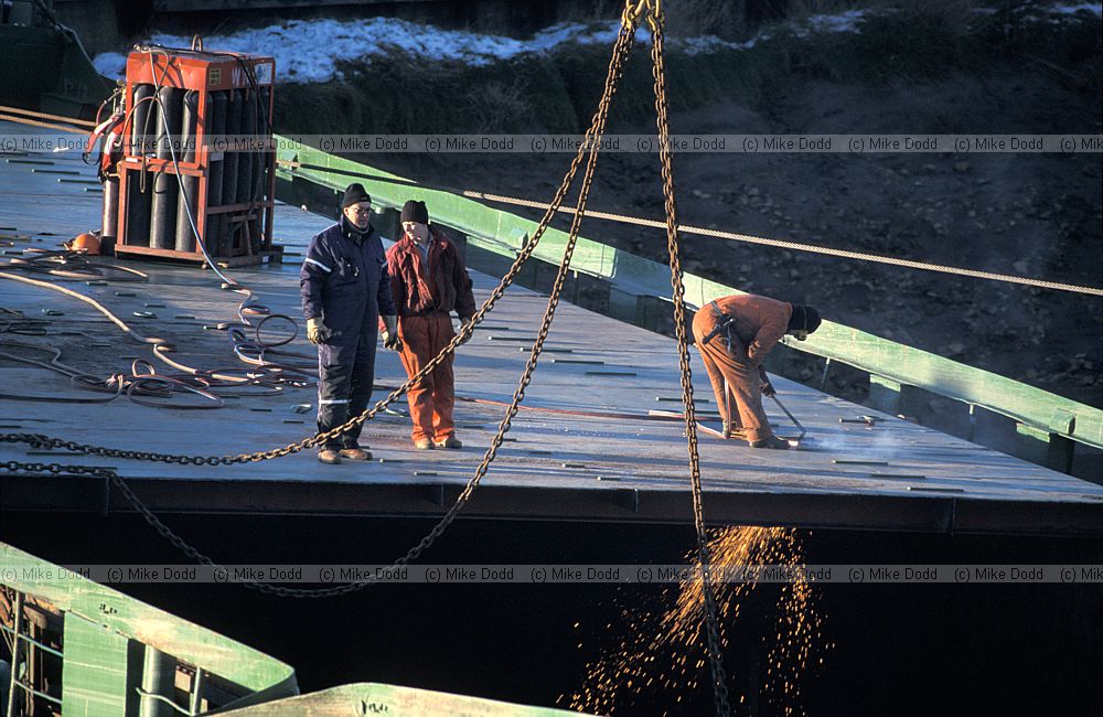 Stuck and broken ship blocking river Nene by Sutton Bridge and being cut up by salvage team