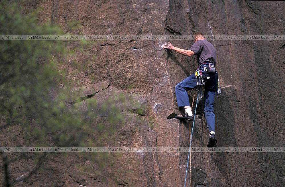 Climber on millstone grit rock Hathersage peak district