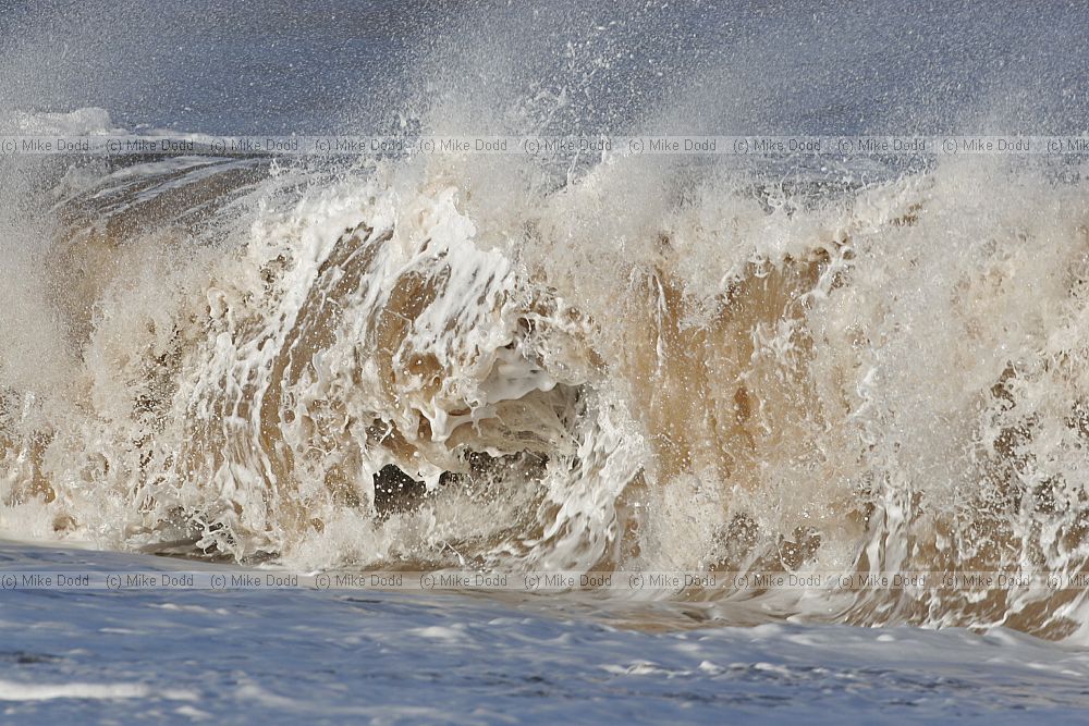 Dramatic wave crashing onto beach