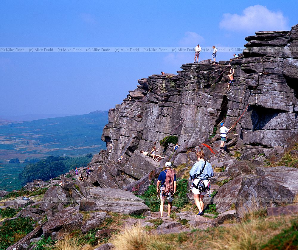 Climbers on millstone grit rocks Stannage edge Peak District