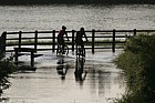 Cyclists struggling through summer flood river Ouzel