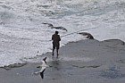 Man fishing from rocks with raging sea