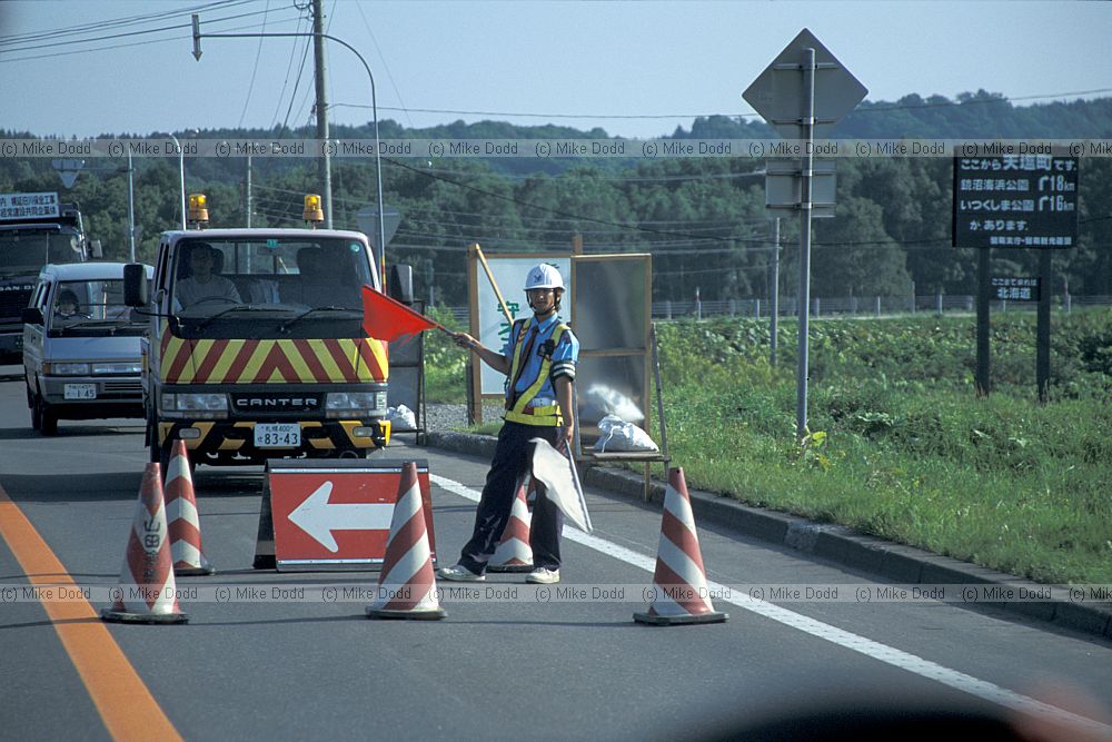 Roadworks traffic being directed by man and flags