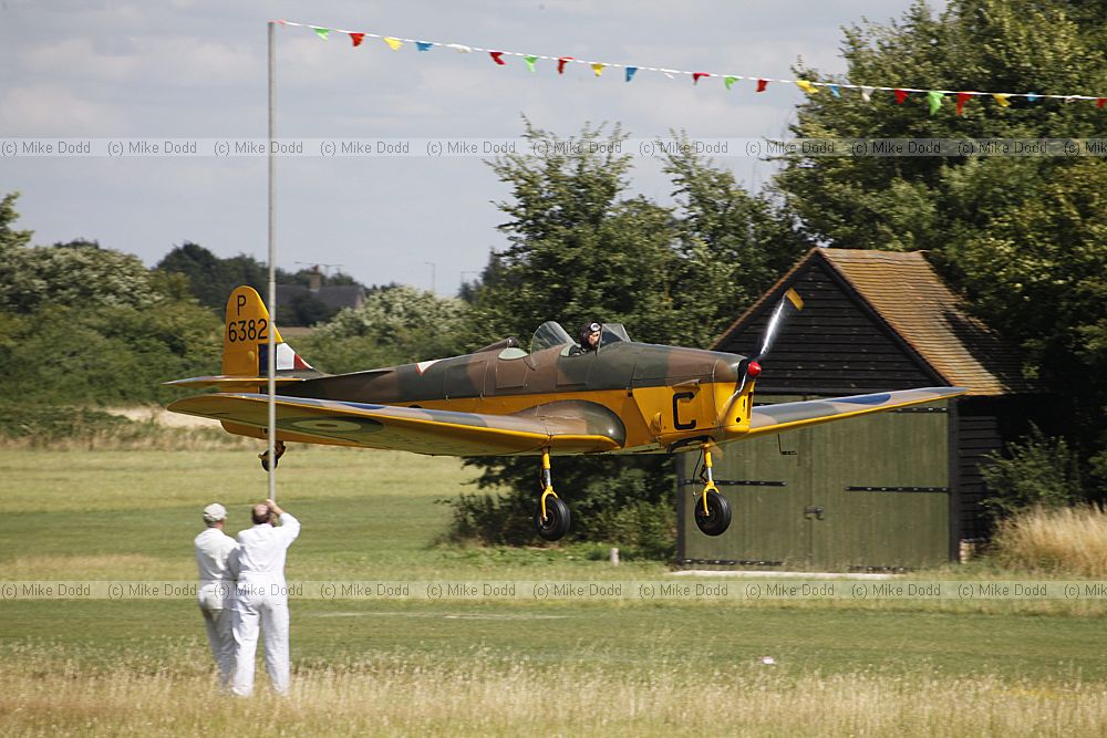 Miles Magister P6382 flying under a banner held up by groundstaff