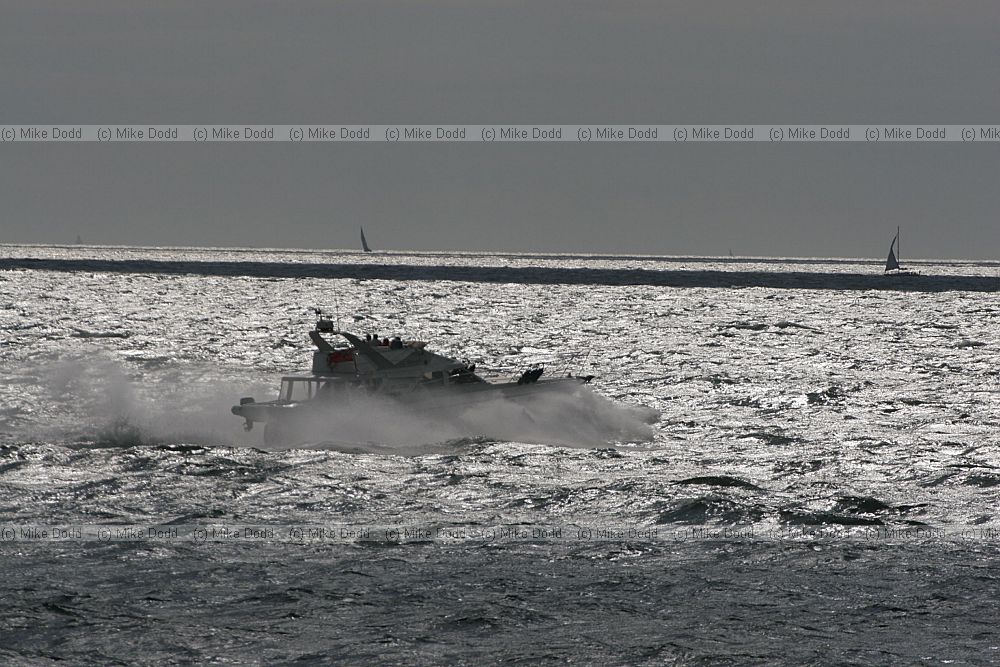 Speedboat crashing through waves against the light