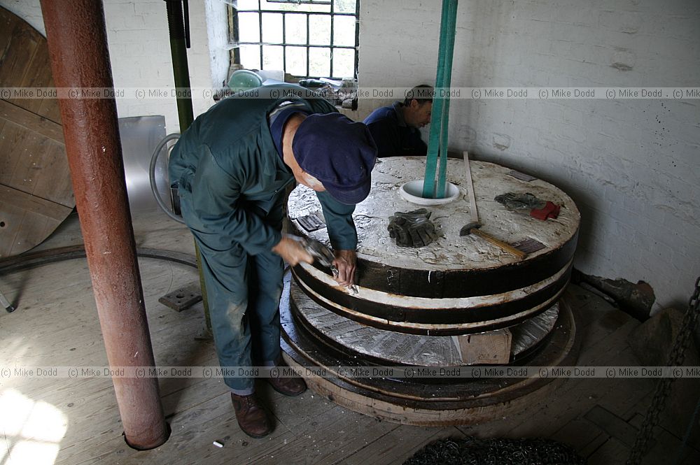 workmen making a hole in millstone so it can be turned over for refacing